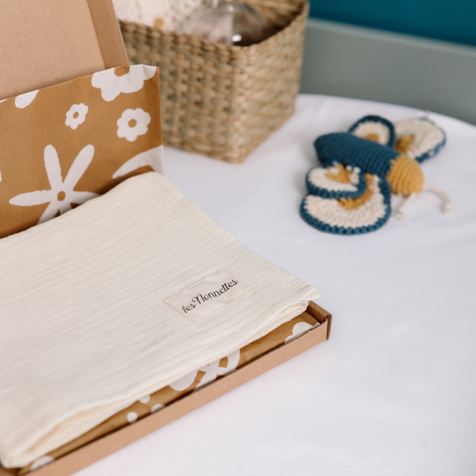 Photo d’un coffret cadeau de naissance les Nonnettes posé sur un lit pour enfant